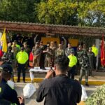 Fotografía de una Rueda de Prensa de la Fuerza Pública en Riohacha, La Guajira. En el centro de la tarima, autoridades militares y de la Policía Nacional acompañan al Presidente durante sus declaraciones institucionales tras el operativo contra alias 'El Bendito Menor'. Al frente se observan periodistas registrando el evento y elementos incautados sobre una mesa.