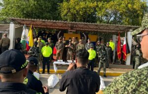 Fotografía de una Rueda de Prensa de la Fuerza Pública en Riohacha, La Guajira. En el centro de la tarima, autoridades militares y de la Policía Nacional acompañan al Presidente durante sus declaraciones institucionales tras el operativo contra alias 'El Bendito Menor'. Al frente se observan periodistas registrando el evento y elementos incautados sobre una mesa.